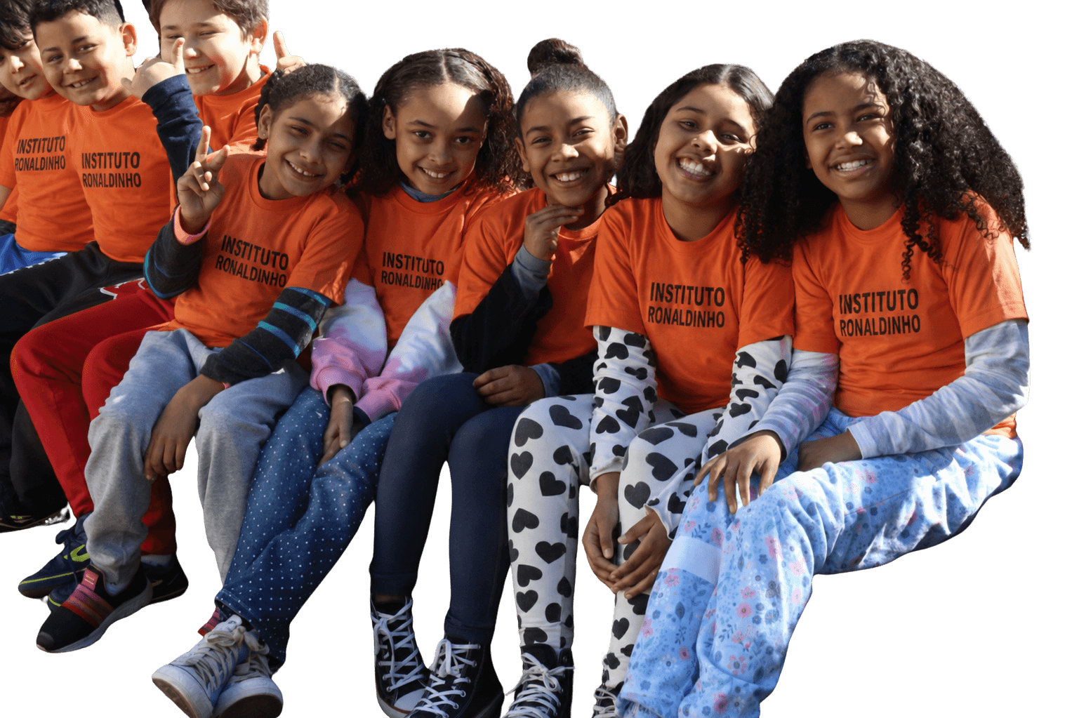 Children in Instituto Ronaldinho shirts sitting together and smiling